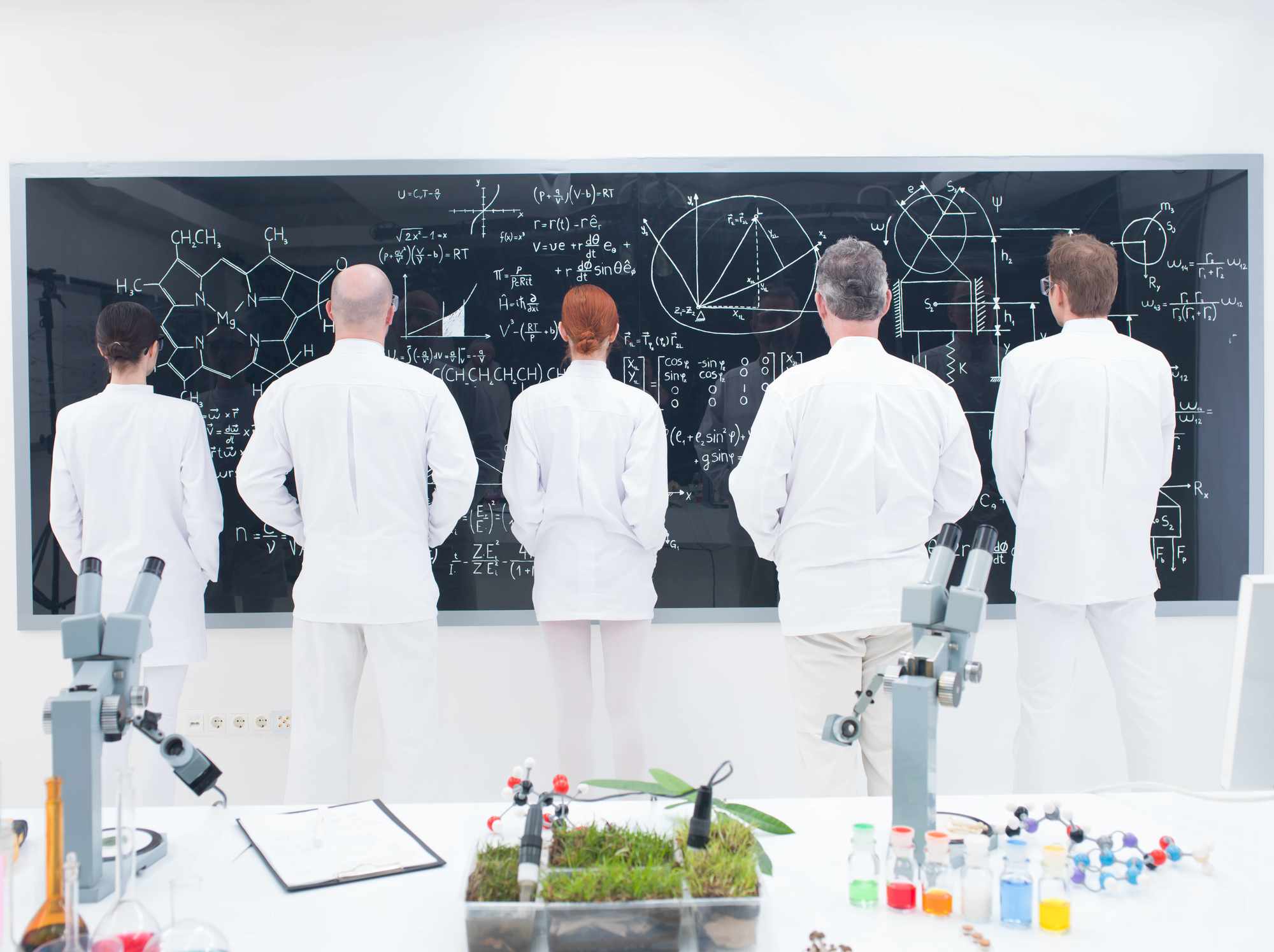 Scientists viewing a whiteboard with scientific depictions.